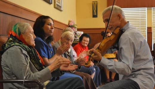 Person playing violin for small group of people